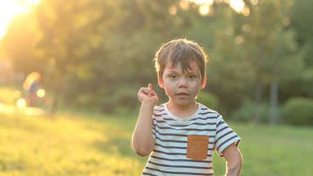 Portrait of a little boy who raised his finger up, photo in nature with copy spaceの写真素材
