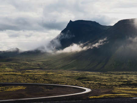 Route to Thrihnukagigur volcano, Iceland. Photograph taken in July. morning view of black volcanic mountain and route below. Black and lichen grenn, cloud sky, slight sunの写真素材