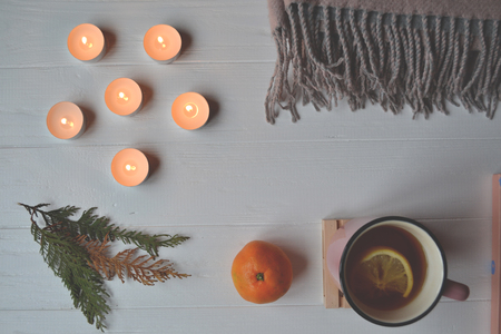 Cozy place. Atmospheric place. Stylish background with a cup of tea, lighted candles, and other decoration elements.の写真素材