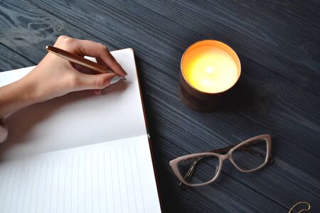 Woman writing in the notebook. Stylish objects on the wooden table. Atmosphere of relax.の写真素材