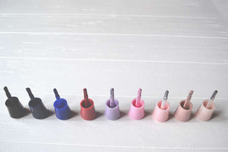 Palette of nail polish on the white wooden background with place for text. Manicure salon.の写真素材