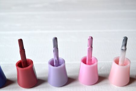 Palette of nail polish on the white wooden background with place for text. Manicure salon.