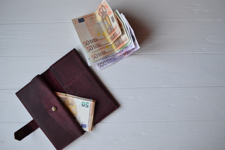 Euro money banknotes and wallet on the white wooden desk. Business money background.