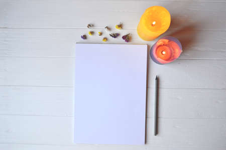 White paper and pencil with decoration on the white wooden desk, top view.の写真素材