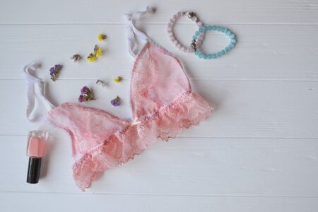 Woman's accessories on the wooden desk. Beautiful lace lingerie, armlets, flowers and nail polish.の写真素材