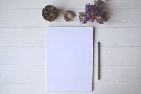 White paper and pencil with decoration on the white wooden desk, top view.の写真素材