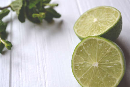 Lime and mint on the white wooden background.