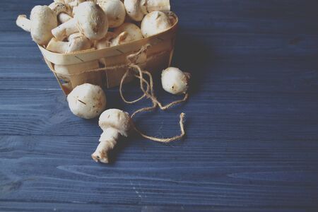 Mushrooms on the dark blue wooden desk. Cooking champignons.