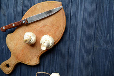 Mushrooms on the dark blue wooden desk. Cooking champignons.の写真素材
