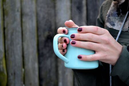 A mug of tea in cold weather. A cup of tea in a woman's hands.