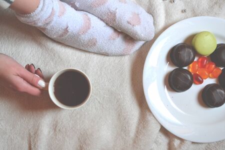 Woman relaxing in a cozy place with sweets and a cup of tea.