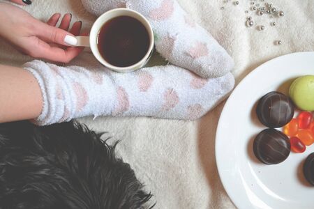 Woman relaxing in a cozy place with sweets and a cup of tea.の写真素材