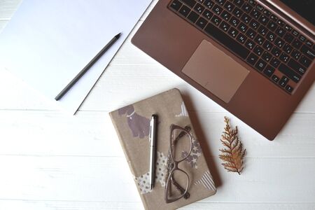 Office table with laptop, notebook, pen, pencil, glasses, wallet and white paper. Stylish office tems.の写真素材