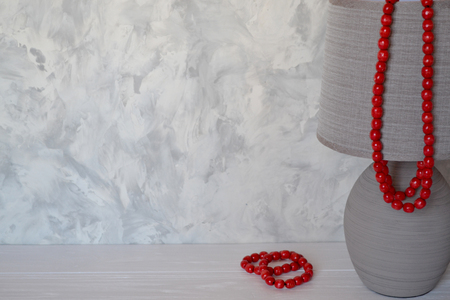 Gray lamp decoration with red beads necklace on the white desk.の写真素材