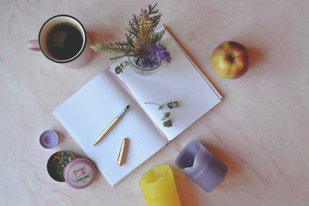 Vintage backgound for greeting card. Beautful flat lay. Apple, bouquet in vase, opened notebook on the pink concrete table.の写真素材