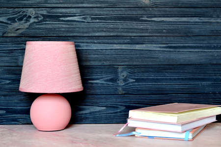 Pink table lamp and books on the desk. Bright background with place for text.の写真素材