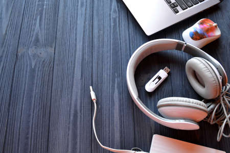 Laptop, mouse, headphones, usb and power bank on the dark blue wooden desk. Electronic device on the workplace. Technology background.の写真素材