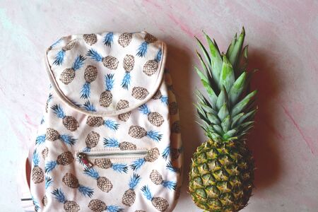 Pineapple and backpack on the table. Summer flat lay.の写真素材