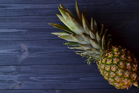 Pineapple on the dark blue wooden table. Summer flat lay. Background with place for text.の写真素材