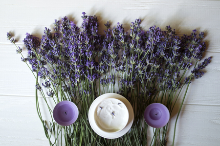 Lavender flowers, candles and cream on a white wooden background. Beauty care.の写真素材