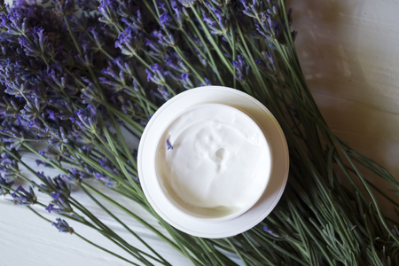 Lavender flowers, candles and cream on a white wooden background. Beauty care.の写真素材