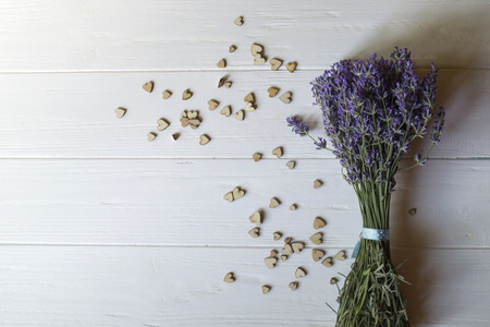 Bouquet of lavender and wooden love hearts on a white wooden table. Beautiful romantic background with copy space.の写真素材