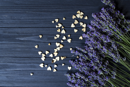 Lavender flowers and wooden love hearts on a dark blue wooden table. Beautiful romantic background with copy space.の写真素材