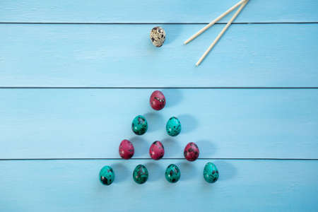 red and blue quail eggs in the shape of a triangle for billiards, bowling on blue backgroundの写真素材