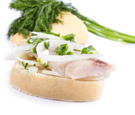 Sandwiches of white bread with herring, onions and herbs on white background