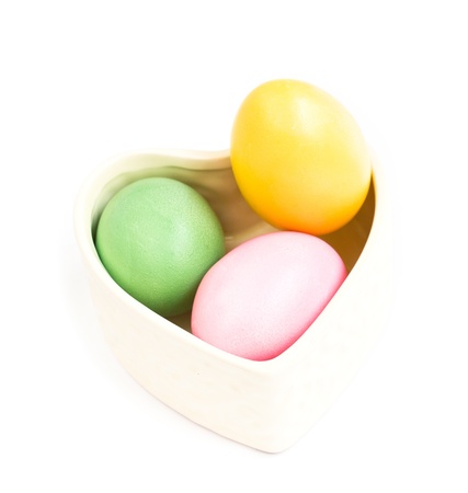 Heart shaped box full of colorful Easter eggs on white backgroundの写真素材