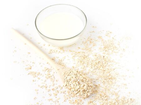 Oatmeal in the wooden spoon and milk  on white backgroundの写真素材