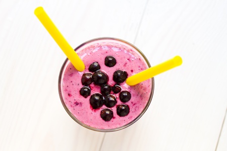 Blueberry smoothie with two straws close up, on white wooden backgroundの写真素材