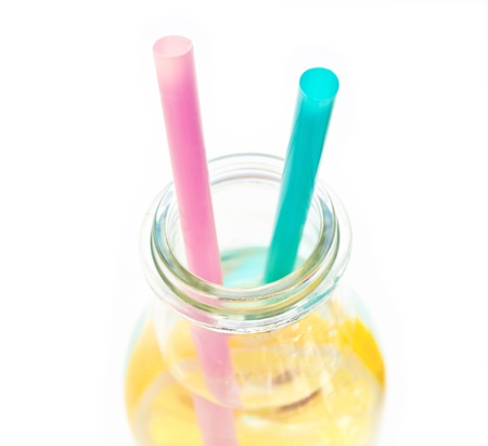 Cold lemon water in a  glass with two straws, isolated on white backgroundの写真素材