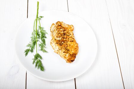 Grilled tasty chicken breasts on a white plate with fresh herbs on wooden backgroundの写真素材