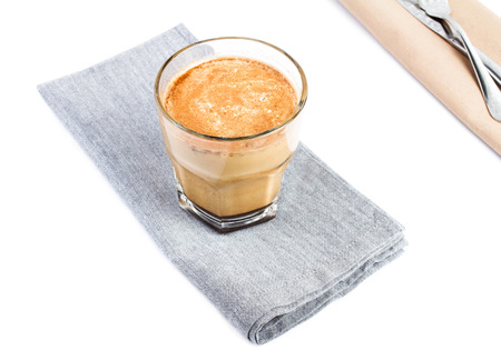 Coffee with milk in a glass cup on linen tablecloth isolated on white backgroundの写真素材