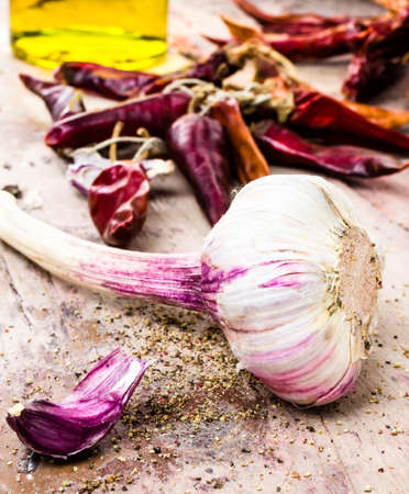 Garlic, red pepper and olive oil on old dark wooden background closeup. の写真素材