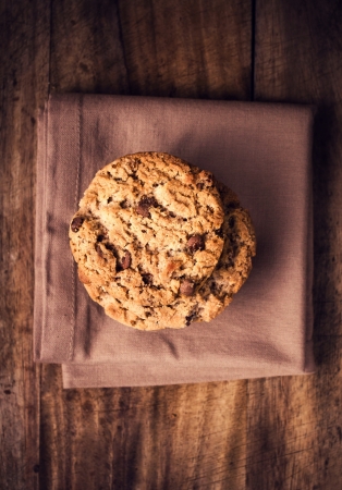 Stacked chocolate chip cookies on dark napkin in country style. Chocolate chip cookies shot on wooden table with selective focus, top view.の写真素材