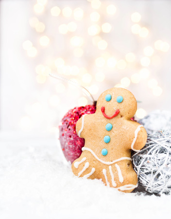 Christmas card with Gingerbread Man cookie, festive decorations and Christmas lights with copy space for greeting text.  Twinkling  red apple on white snow.の写真素材