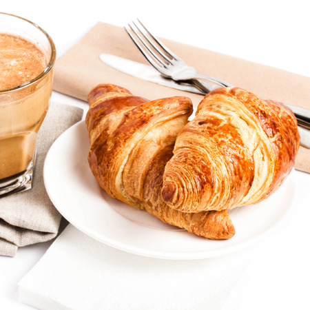 Breakfast with Coffee cup and  Croissants on a plate and linen napkin  isolated on white background, closeup.の写真素材