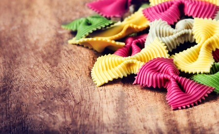 Fresh Fresh Italian Pasta on old vintage wooden background. Raw Bow tie colourful  pasta close up.の写真素材