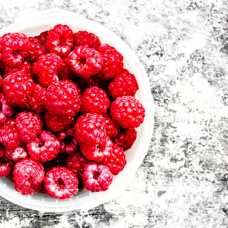 Fresh Red Raspberry in a white bowl over textuted background, close up. Summer or Spring Natural...