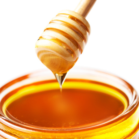 Honey Dipper with honey in jar isolated on white background macro