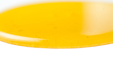Yellow honey flowing liquid  drop  isolated on white background macro.の写真素材
