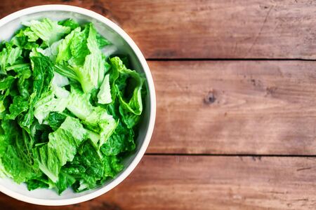 Fresh Green salad in a white bowl on rustic background with copy space for text. Lettuce leaves, top view imageの写真素材
