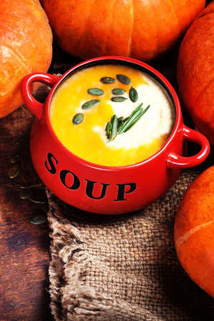Pumpkin soup with fresh pumpkins and bread crouton on wooden table. Bowl of pumpkin soup with copy space close upの写真素材