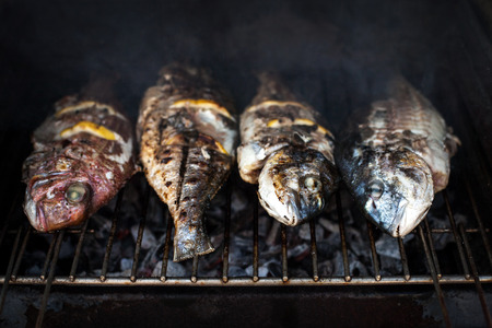 Grilled fish with spices on fire close up. Grilling fish  dorado on campfire