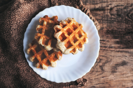 Plate of  belgian waffles with icing sugar close up on wooden table with copyspace