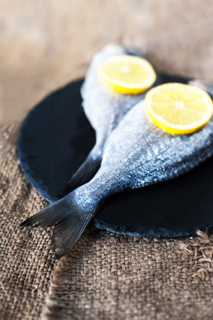 Fresh raw Dorado sea  fish on wooden  board with  lemon and salt. Top viewの写真素材
