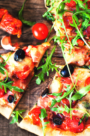 Hot pizza slice with Pepperoni, melting cheese on a rustic wooden table close up.
の写真素材