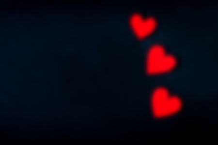 Blurry defocused Red hearts over black background - Saint Valentines day concept card with empty space for textの写真素材